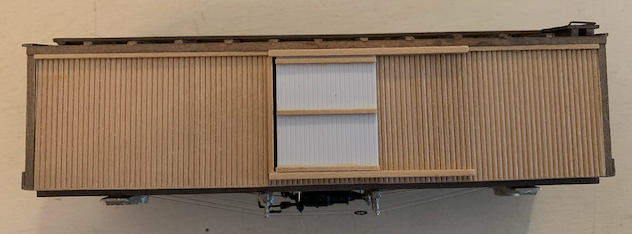 Unpainted side of a wooden HO scale box car kit with composite wood-braced styrene doors.