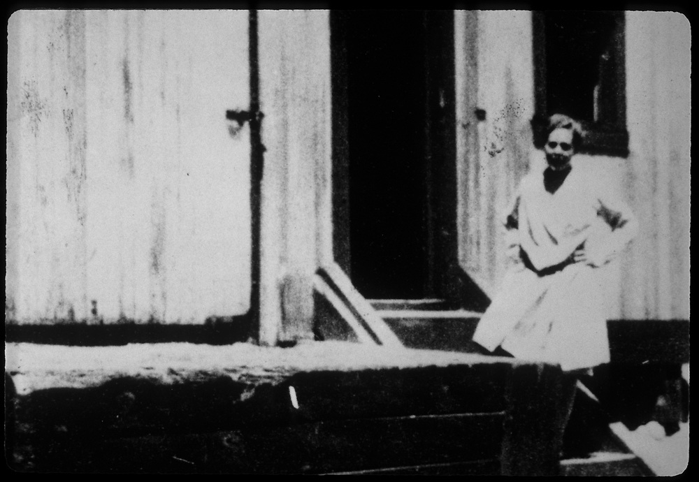 Edith Warner posing in front of a box car converted into a small rail station. Black and white, ca. 1940.