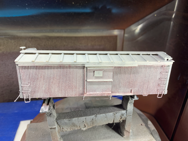 HO scale wooden box car with a fresh coat of gray primer.