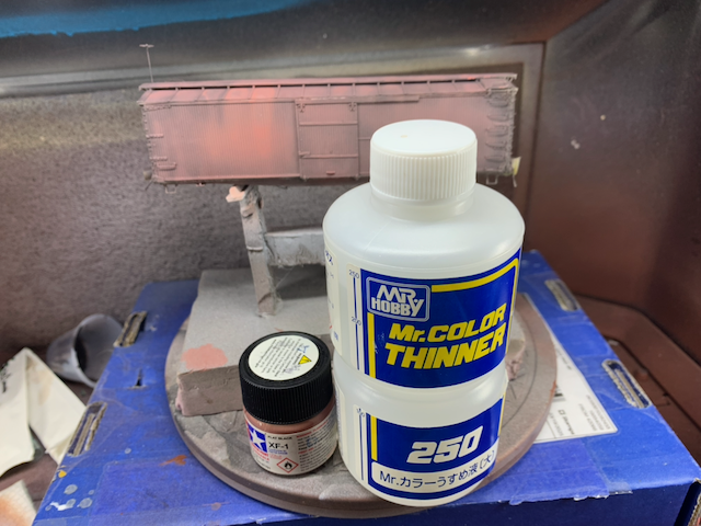 HO scale box car in a spray booth behind Mr. Color thinner and a custom pink paint mixture.