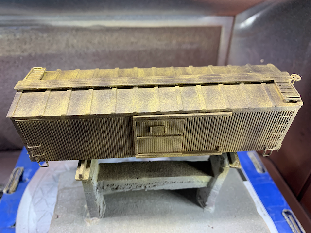 HO scale wooden box car with a layer of gray-black on top of depot buff.