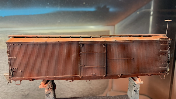 HO scale box car being painted, side view.