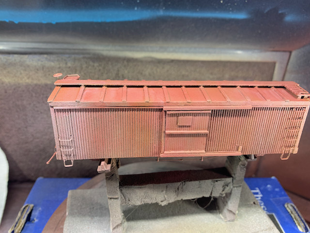 HO scale wooden box car with some gray aging applied on top of the box car red color.