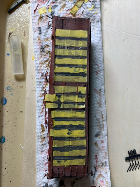 Dark gray weathering of boards between Tamiya masking tape stripes on the side of an HO scale UP box car.