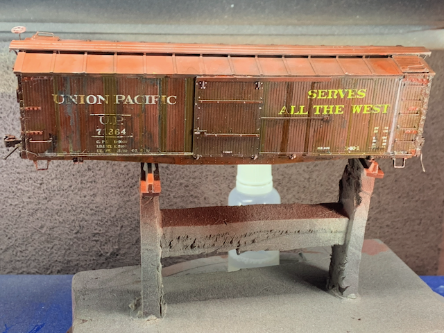Heavily weathered HO scale UP box car in the paint booth next to a bottle of Pledge being used as a semi-gloss coat.