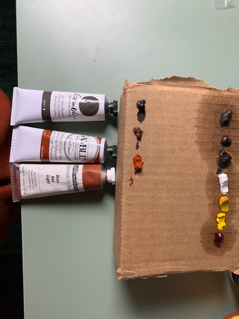 More reds being added to the oil paint palette on cardboard. The original line of colors has soaked linseed oil into the cardboard.