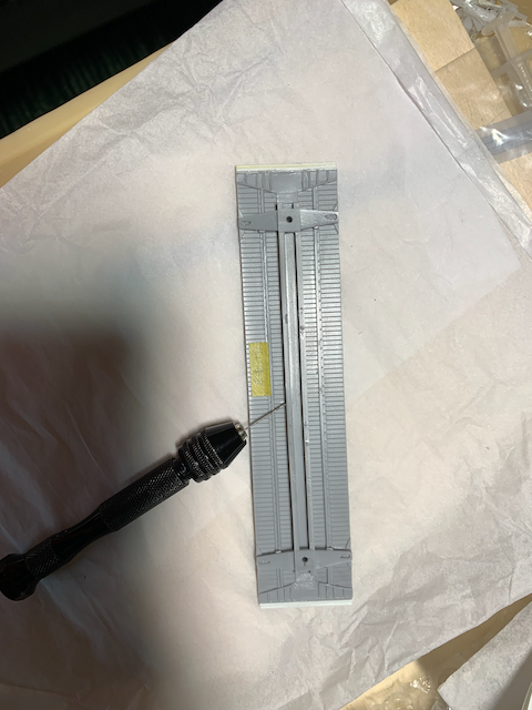 Resin HO scale box car floor being drilled out for the trainline.