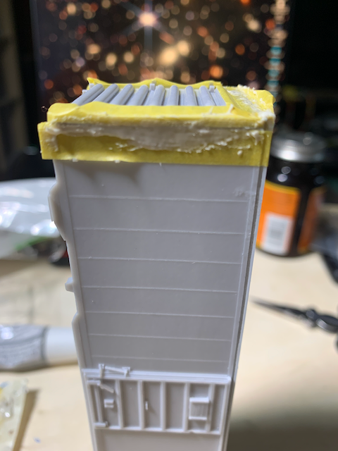 HO scale box car with the side and ends masked and Tamiya putty being used to fill the gap between the end and side.