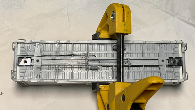 Inverted HO scale box car clamped together while the glue dries.