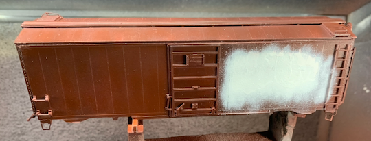 HO scale box car being spot repainted from the white primer layer up.