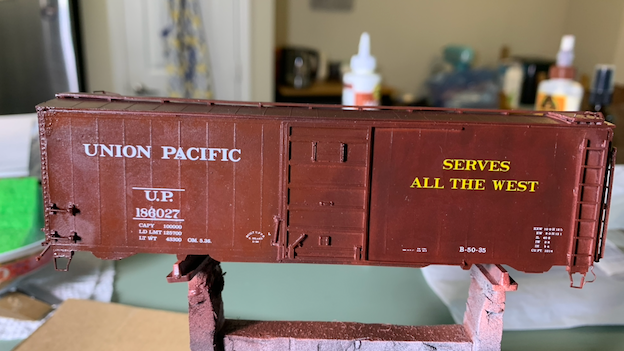 HO scale UP box car on a painting stand with decals applied.